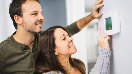Husband and wife looking at smart thermostat